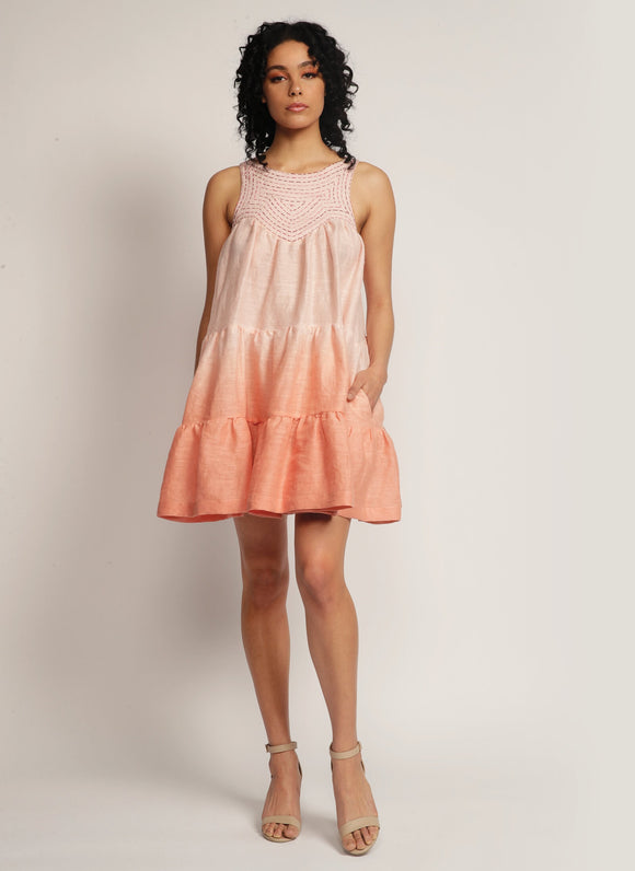 Woman standing in a dip-dyed pink sleeveless dress with hand embroidered detail on the yoke