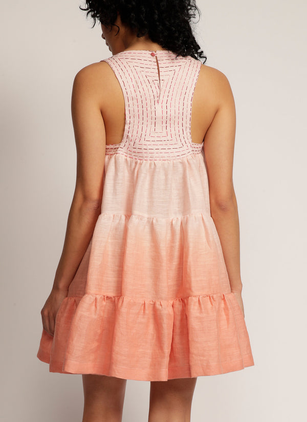 Back view of a woman standing in a dip-dyed green sleeveless dress with hand embroidered detail on the yoke