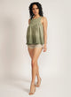Woman wears a dip-dyed sleeveless top with pom-pom trim and hand embroidered detail with beige shorts