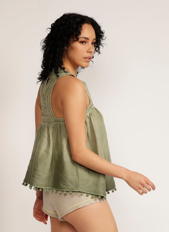 Close up back view of a woman wearing a dip-dyed sleeveless top with pom-pom trim and hand embroidered detail with beige shorts