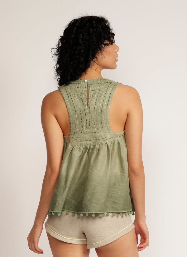 Back view of a woman wearing a dip-dyed sleeveless top with pom-pom trim and hand embroidered detail with beige shorts