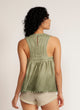 Back view of a woman wearing a dip-dyed sleeveless top with pom-pom trim and hand embroidered detail with beige shorts