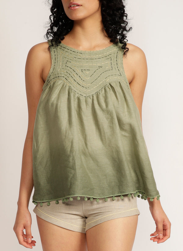 Close up of a woman wearing a dip-dyed sleeveless top with pom-pom trim and hand embroidered detail with beige shorts