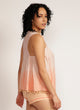 Close up of a woman wearing a dip-dyed sleeveless pink top with pom-pom trim and hand embroidered detail with pink shorts