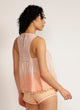 Back view of a woman wearing a dip-dyed sleeveless pink top with pom-pom trim and hand embroidered detail with pink shorts