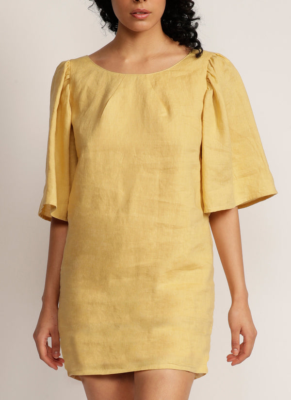 Close up of a woman wearing a yellow mini dress with oversized bell sleeves