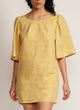 Close up of a woman wearing a yellow mini dress with oversized bell sleeves