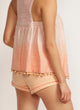 Back view of a woman wearing apricot shorts with pink piping detail and a pink top