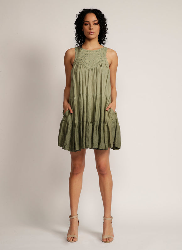 Woman stands in dip-dyed green sleeveless dress with hand embroidered detail on the yoke