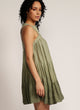 Side profile of a woman standing in a dip-dyed green sleeveless dress with hand embroidered detail on the yoke