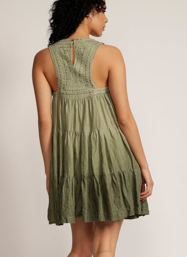 back view of a woman standing in a dip-dyed green sleeveless dress with hand embroidered detail on the yoke