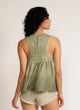 Back view of a woman wearing a dip-dyed sleeveless top with pom-pom trim and hand embroidered detail with beige shorts