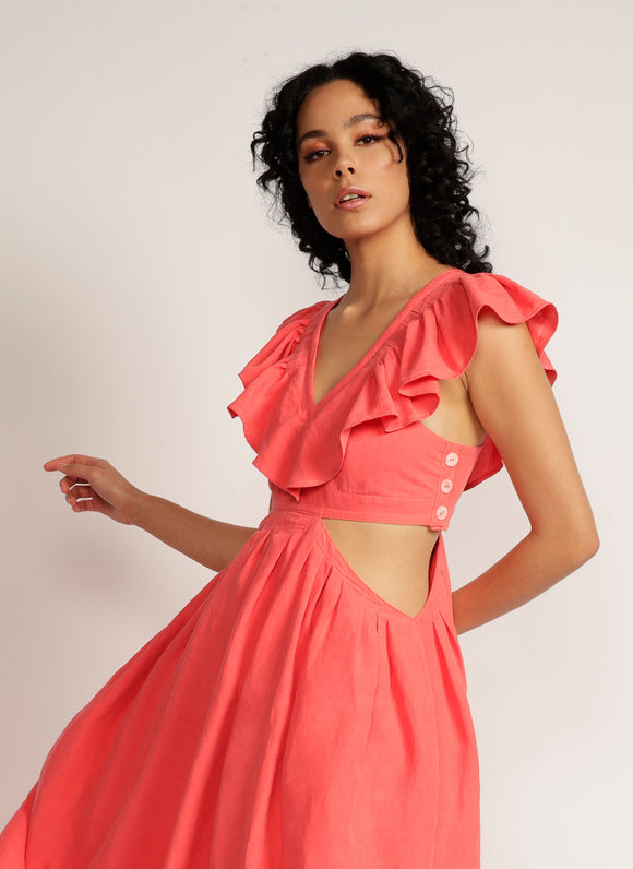 Close up of woman wearing a pink maxi dress with cutout detail and ruffle neckline