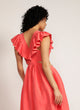 Back view of a woman wearing a pink maxi dress with cutout detail and ruffle neckline