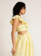 Side view of a woman wearing a yellow maxi dress with cutout detail and ruffle neckline