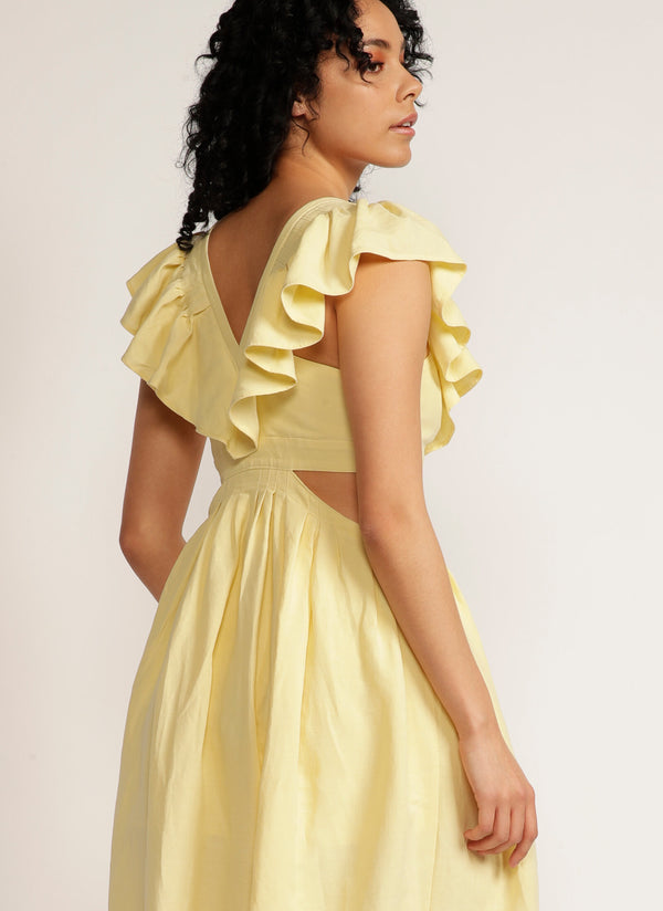Back view of a woman wearing a yellow maxi dress with cutout detail and ruffle neckline
