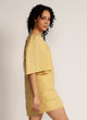 Side view of a woman wearing a yellow mini dress with oversized bell sleeves