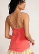 Back view of a woman wearing a pink camisole with pom pom strap detail and matching skirt